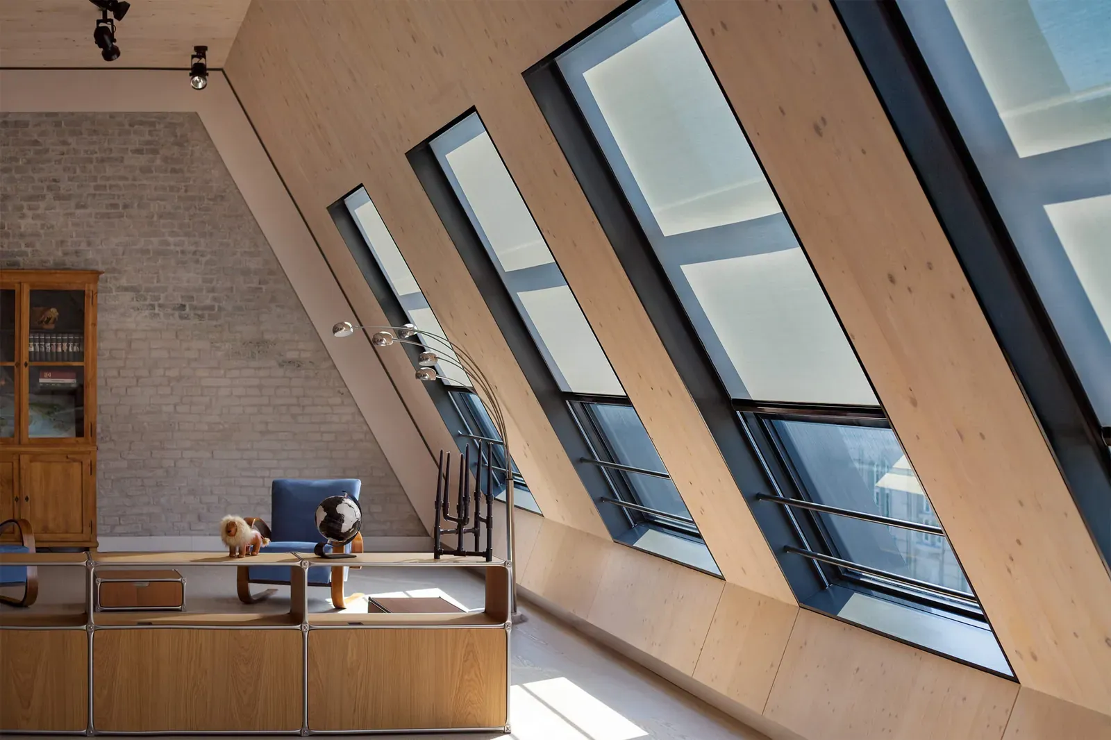 Schräge Dachfenster mit Rollos über einem Sideboard mit Leuchte