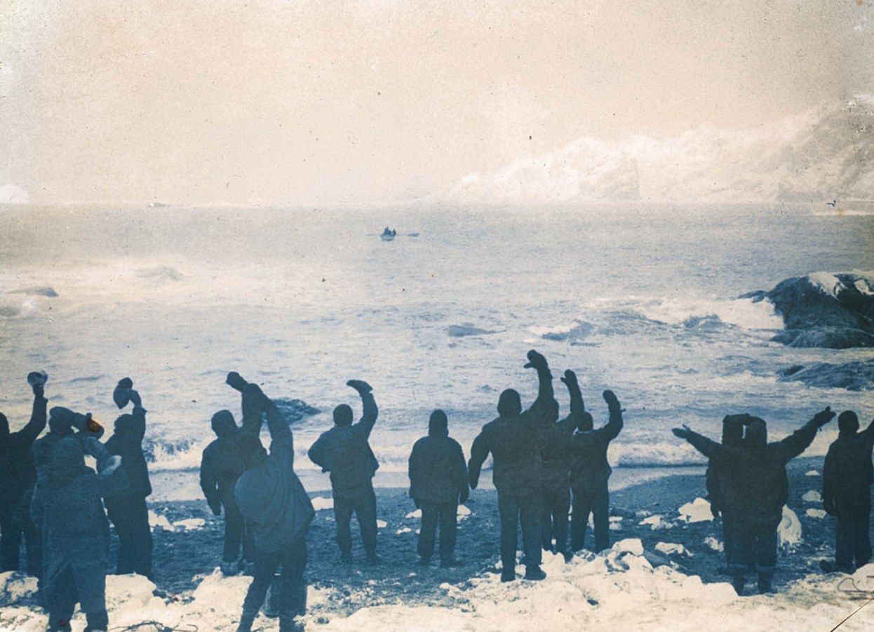 Shackletons Mannschaft winkt der James Caird nach, die am 24. April 1916 Elephant Island verlässt — Foto: Frank Hurley